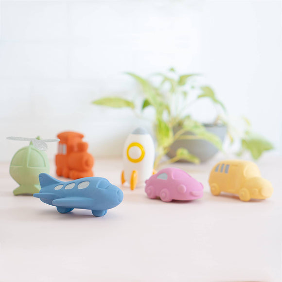 Colorful toy vehicles on a light surface with a blurred plant in the background