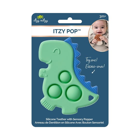 Itzy Ritzy Itzy Pop in the package. The package is blue and says, "Itzy Pop" with an image of a baby holding a mushroom popper with a rust color top and tan stem. In the middle is the dinosaur Itzy Pop. It is green silicone with blue spikes and 3 popping bubbles in the middle. Along the bottom, it says, "Silicone Teether with Sensory Popper."