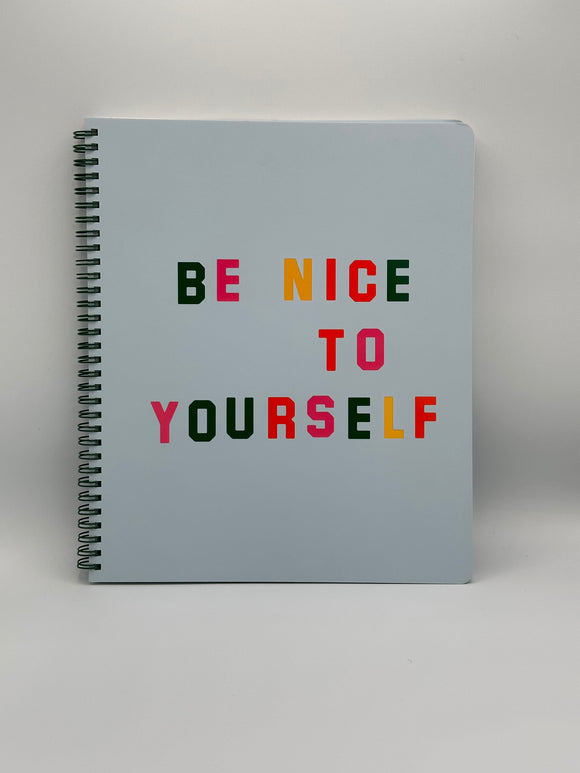 The cover of the Ban-do Be Nice Rough Draft spiral-bound notebook. It has a green spiral, light blue cover, and says, "be nice to yourself" with alternating green, pink, yellow, and orange letters