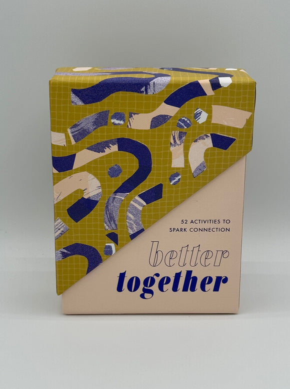 The front of the Better Together box. The lid is chartreuse with dark blue and light pink squiggles. It slants down the middle of the box. The box is light pink and says, "52 activities to spark conversation" in thin blue letters and, "better together" in bold blue letters.