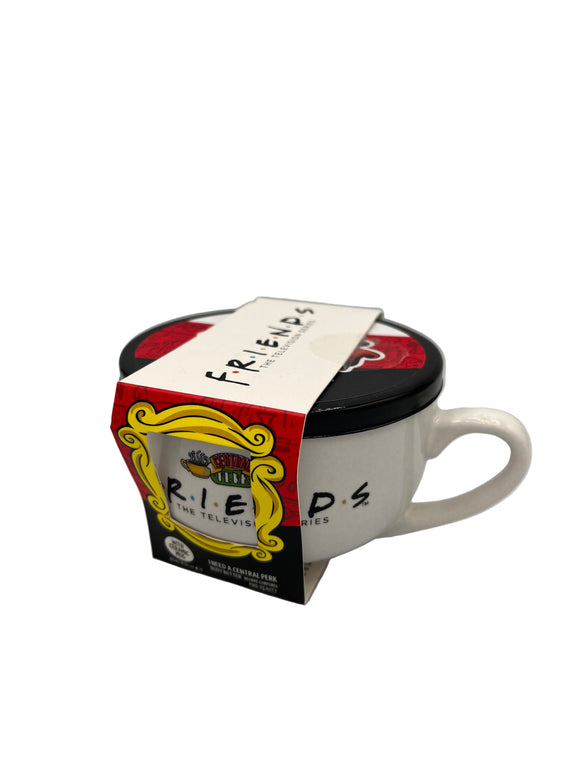 White, mug shaped container that says, "Friends, the television series" in black. Above the writing, there is an image of two steaming yellow coffee mugs surrounding a green, yellow, and red sign that says, "Central Perk". The container has a black lid with a white, red, and black stripe. Around the container, there is a paper label. The top is white and says, "Friends, the television series" in black. The front is half red and half black with a yellow frame cutout that shows the writing on the container.