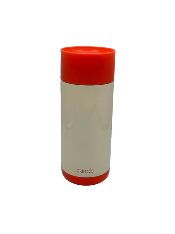 The back of the Ban-do Bold Move mug. It is cream with a red lid and red bottom and says 'ban-do' in small, thin, red letters at the bottom.