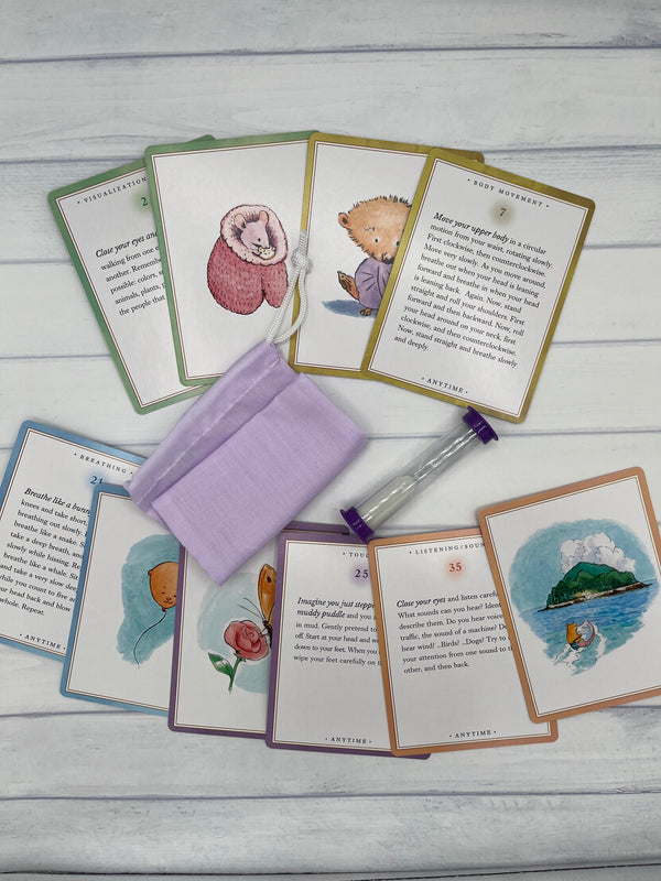 10 exmples of the Eeboo Anytime Centering Cards. In the middle of the cards is a purple pouch and a purple sand timer.