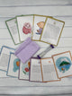 10 exmples of the Eeboo Anytime Centering Cards. In the middle of the cards is a purple pouch and a purple sand timer.