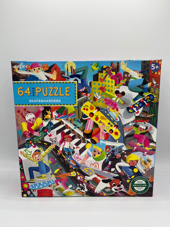 The front of the Eeboo Skateboarders Puzzle box. There is a small light blue box in the corner that says, "64 piece puzzle Skateboarders" and the rest of the cover is a picture of the puzzle. It contains a city scape with skateboarders riding various different color skateboards and wearing various colored helmets doing different tricks.