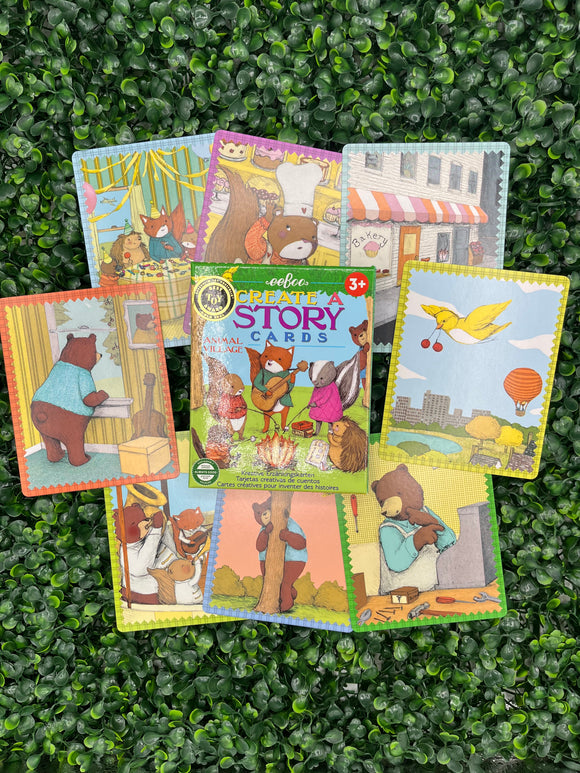 The eeboo animal Create a Story Cards. The box is in the middle and has a fox playing guitar, a sunk, a squirrel, a bear, and a hedgehog roasting marshmallows on the front. Surrounding the box are examples of the story cards. Each of them have a different animal doing a different activity.