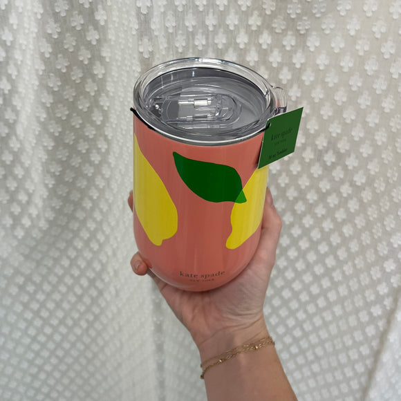 Top view of the Lemon Toss Wine Tumbler. The lid is clear with a plastic sliding piece to reveal the mouth opening. The tumbler is peach with yellow lemons and green leaves and says, "kate spade, New York" in gold on the bottom.