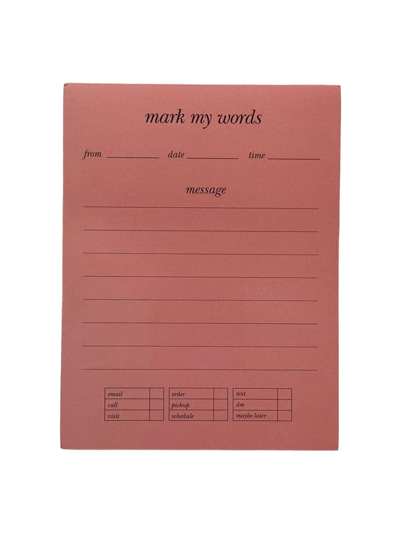 Kate Spade Mark My Words notepad. The notepad is pink with gold edges. The pages says, "mark my words, from, date,time, message" and under 'message' there are lines to write. At the bottom there are 3 charts. One says, "email, call, visit," one says, "order, pickup, schedule," and the other says, "text, dm, maybe later."