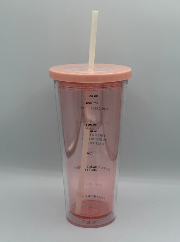 The side of the Ban-do Sip Sip Tumbler. It is clear pink with a pink lid and white straw. There are markings for 8 oz, 300 mL, 16 oz, 500 mL, 650 mL, and 24 oz. The oz markings are shown with a gold squiggly line and the mL markings are shown with a gold straight line.
