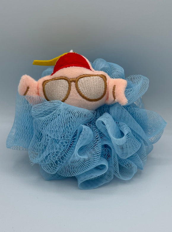 A blue loofa with a pinkish/tan raw turkey plush wearing brown glasses and a red hat.