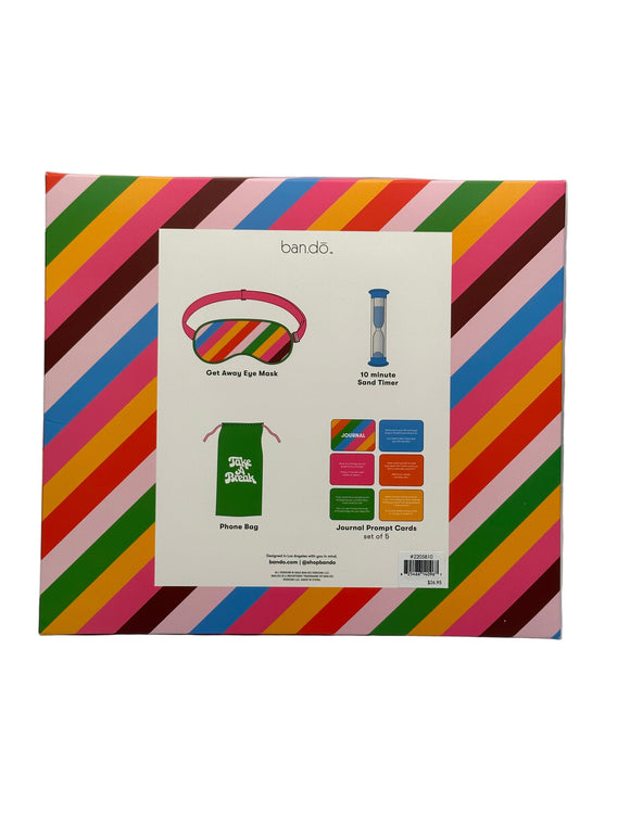 The back of the Ban-do Unplug Kit box. It shows pictures of each of the items (a get away eye mask, a 10 minute sand timer, a phone bag, and a set of 5 journal prompt cards) along with what each of the items are under the photo.