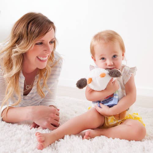 Woman and child lying on a white surface with a plush toy