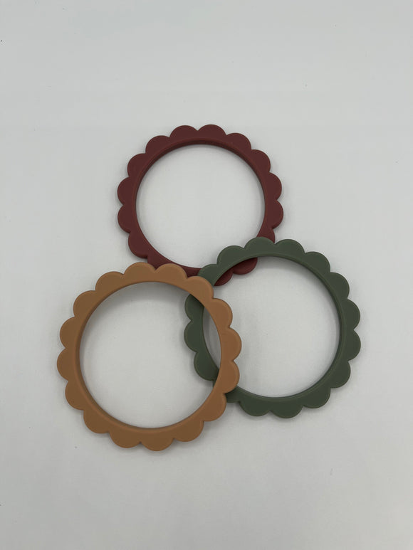 The dried thyme, berry, and natural rings out of the pack. In the back is the berry (maroon) ring, on the right is the dried thyme (sage green) ring, and on the left is the natural (brown) ring.