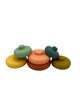 The pieces of the OB Designs Tower Stacker laid out randomly. From left to right, there is a yellow piece with a mint green piece on top of it, a red piece with a light pink piece on top of it, and an olive green piece with a teal piece on top of it.