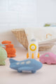 Colorful baby toys including a blue airplane, orange car, and pink boat on a light surface with a blurred background.