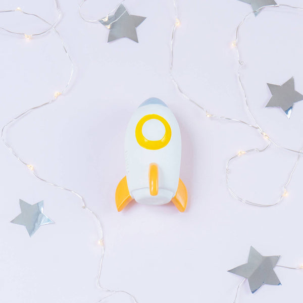 Toy rocket ship with a yellow circle on a light gray background with star decorations