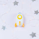 Toy rocket ship with a yellow circle on a light gray background with star decorations