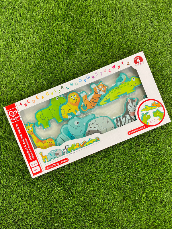 Hape alphabet and animal parade. The box is white with a rainbow alphabet across the top with a clear film in the middle to see the product inside. The product is a puzzle of animals (dinosaur, lion, tiger, alligator with a bird on top, giraffe, elephant, hippo, and zebra). They all connect to each other with a teal outline around the whole puzzle.
