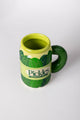 Green mug with leaf design and 'Pickles Crunch' text on a white background