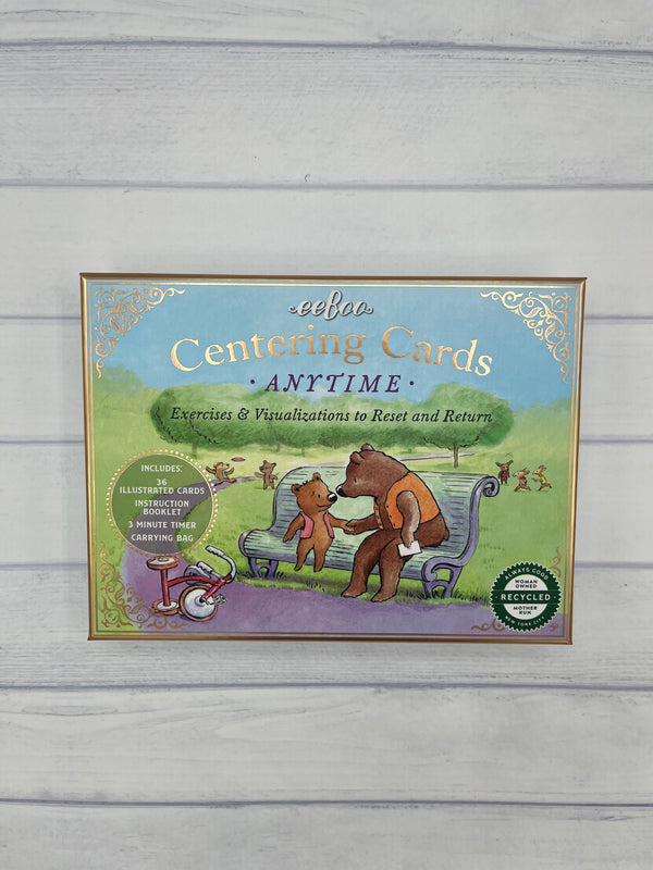 A light blue box with a gold border that says, "eeboo Centering Cards Anytime Exercises & Visualizations to Reset and Return". There are two bears sitting on a bench in a park with trees in the background.