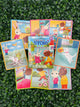 The Eeboo very busy day create a story cards. The box is a garden scene with a bunny in a pink dress and a bear dressed as a sailor. Surrounding the box are examples of the cards. Each card contains an animal doing a different daily activity.