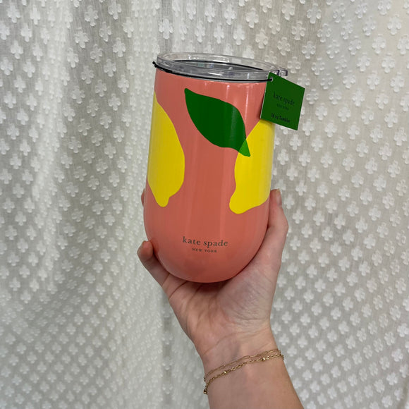 A hand holding a peach, metal wine tumbler with yellow lemons and green leaves. The tumbler has a clear lid.