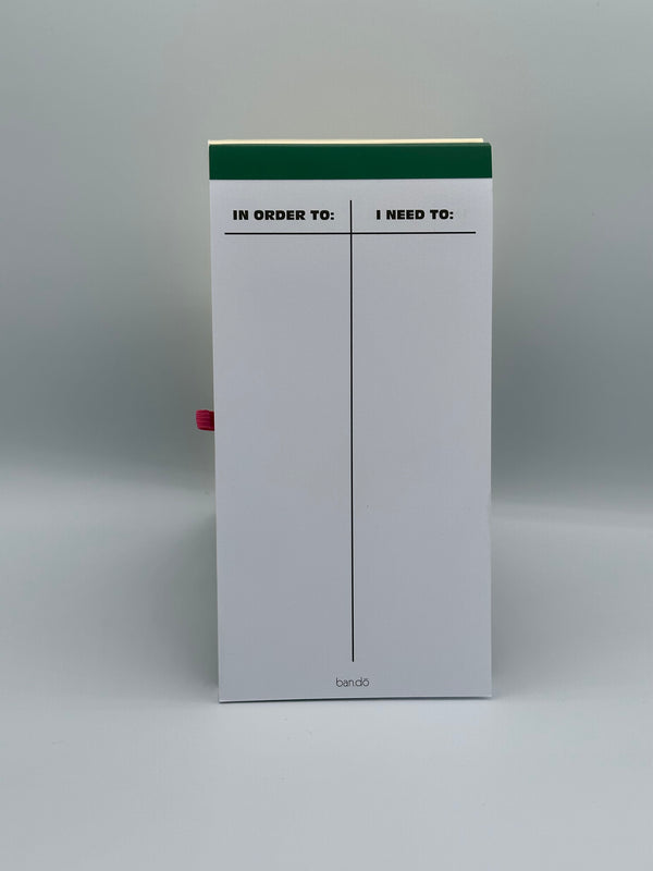 The inside of the Ban-do Progress Not Perfection goal tracker. It has plain white pages with a T chart. On one side of the chart it says, "In order to:" and on the other side it says, "I need to:"
