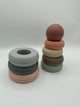 The original Mushie Stacking Rings tower split in half. On the left are the 3 largest rings (from bottom to top) in light pink, sage green, and light blue. On the left are the 4 smaller sized rings (from bottom to top) in mint green, taupe, cream, and peach with the dusty pink ball on top. 