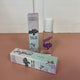 In the back there is the lavender Honestly Margo Roller Girls Lip Gloss box next to the lip gloss. The box is lavender and says, "Roller Girls, Roll-on Lipgloss", and the lip gloss is in a clear tube with a white cap and says, "Roller Girls" in purple. In the front the box is laying on its side. On the top it says, "Jazmin, Grape", and on the side it says, "Roller Girls, Roll-on Lipgloss".