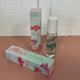 In the back there is the mint green Honestly Margo Roller Girls Lip Gloss box next to the lip gloss. The box is mint green and says, "Roller Girls, Roll-on Lipgloss", and the lip gloss is in a clear tube with a white cap and says, "Roller Girls" in green. In the front the box is laying on its side. On the top it says, "Alexis, Watermelon", and on the side it says, "Roller Girls, Roll-on Lipgloss".